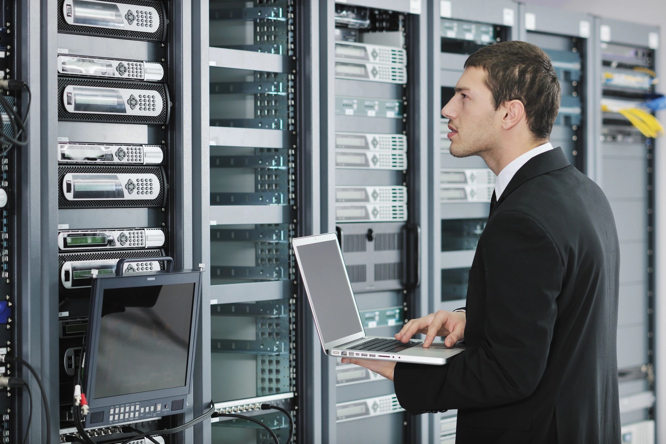 IT professional with laptop beside server racks